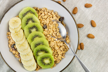 Breakfast with yogurt, kiwi and banana. Plate with granola and fresh fruit. healthy eating style