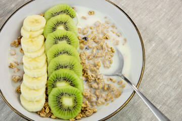 Breakfast with yogurt, kiwi and banana. Plate with granola and fresh fruit. healthy eating style