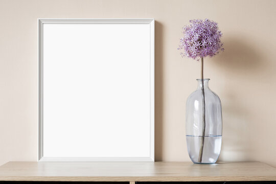Blank picture frame mockup on beige wall. Vertical artwork template in minimal interior design. View of modern style interior with canvas for painting or poster on wall. Minimalism concept