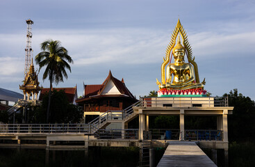 Fototapeta premium A view of a large meditating golden Buddha statue enshrined on a concrete hall structure.