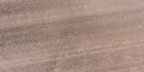 panorama of surface from above of gravel road with car tire tracks