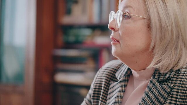Senior woman scratching head, suffering from lack of ideas while writing a book