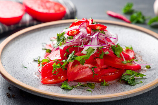 Tomato salad with red onion on plate, achichuk salad, achik chuchuk macro close up