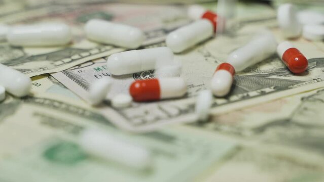 Pills fall from above on dollars. Slow motion. Close-up.