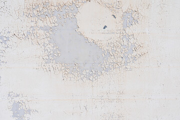 A layer of white paint on a smooth gray concrete wall was cracked and partly peeling off. Background. Texture.