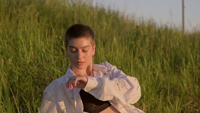 Portrait of woman enjoying nature on field at sunset. Magic female with short haircut. Woman lies on summer field. 4K, UHD