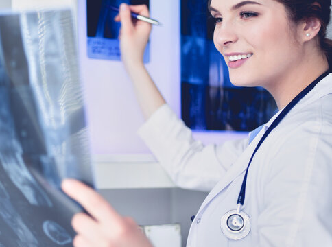 Young professional female doctor examining patient's x-ray