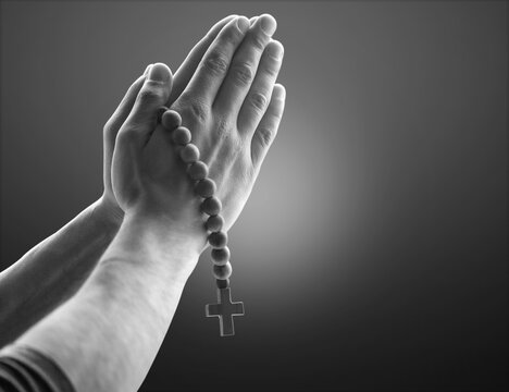 Image black and white hand holding rosary with cross and praying to God at church.