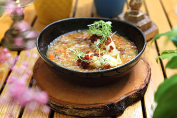 Sauerkraut soup in a modern black bowl, on a wooden table, horizontal view. Cabbage soup with dumplings. 