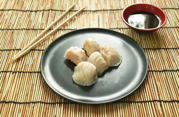 Ha Kao or white dumpling stuffed shrimp and pork on plate dipping soy sauce