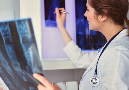 Young professional female doctor examining patient's x-ray