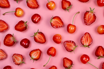 background of ripe strawberries and cherries on a pink background.Trendy,fruity,summer background