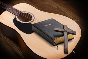 Holy Bible with acoustic guitar and religious crucifix cross on desk, gospel music concept