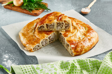 Classic turkish pie with meat on wooden board. Composition with burek pie on concrete background...
