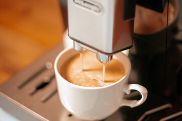 Modern coffee machine with a partially full cup of coffee on table in kitchen