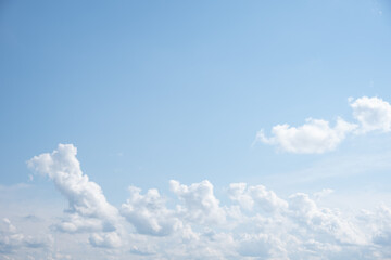 Blue sky background with white fluffy cumulus clouds. Panorama of white fluffy clouds in the blue sky. Beautiful vast blue sky with amazing scattered cumulus clouds.