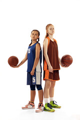 Portrait of two young girls, basketball players posing with basketball ball isolated on white background. Concept of sport, team, enegry, competition, skills