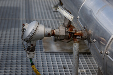 A metal thermocouple in an industrial environment, placed to measure and monitor the temperature in...