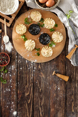 Composition of georgian khinkali on wooden table with coriander leaves. Georgian food - classic and black khinkali in rustic style. Traditional georgian dumplings khinkali on wooden background.