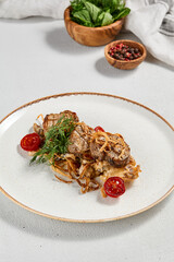 Meat medallions on mashed potatoes and crispy onion. Pork medallions with potatoes garnish and creamy-mushroom sauce. Roasted pork fillet. Main course - Meat steak from pork on ceramic plate