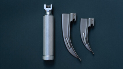 single instrument - laryngoscope for tracheal intubation in a disassembled state.  the tube and blades of different sizes lie on a dark background.  close-up