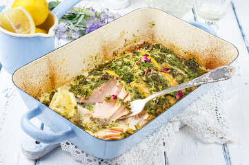 Traditional Italian salmon filet with pesto and lemon slices served as close-up in a frying pan
