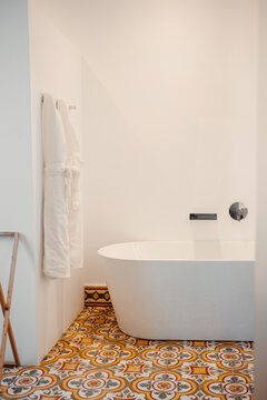 Robes hanging on wall in modern bathroom with oval tub