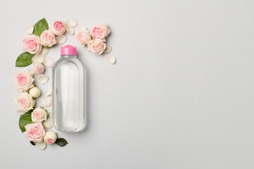 Micellar water with rose flower on color background, top view