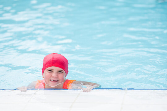 Serious Kid Swimming In Pool And Looking At Camera