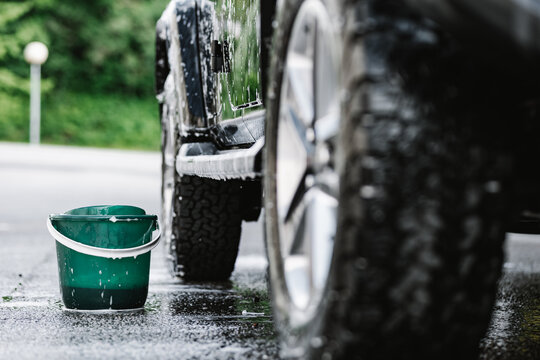 Black Car Covered With Foam During Wash Next To Bucket