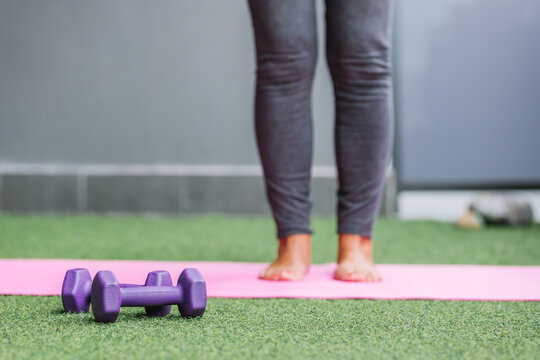 Purple Dumbbells Near Woman Standing On Yoga Mat - Powered by Adobe