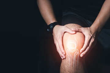 Young man with knee pain, joint pain, arthritis and tendon problems  exercise injury on dark...
