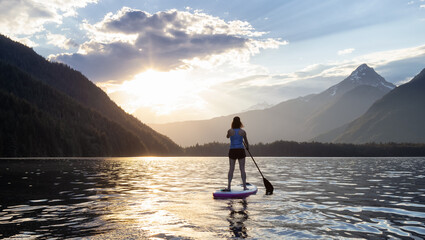 Adventurous Woman Paddle Boarding in a Lake around Canadian Mountain Landscape. Chilliwack Lake,...