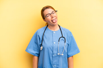 pretty blonde young woman with cheerful and rebellious attitude, joking and sticking tongue out. physician or doctor student concept - obrazy, fototapety, plakaty