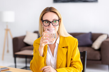 Healthy lifestyle concept. Young business woman drinking clean water sitting workplace in modern...