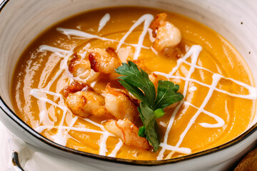 Closeup on pumpkin cream soup with fried shrimp and toasts