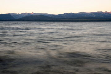 Fototapeta premium Long exposure shot of Nahuel Huapi lake at sunset. Beautiful blurred water effect and mountains in the horizon with dusk colors.