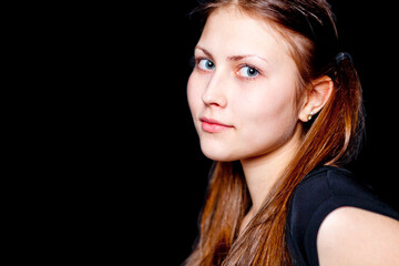Cute girl - brunette looks at the camera. Black background
