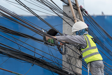 An electrical engineer checks and repair the fiber optics system on a power pole,. to engineer and...