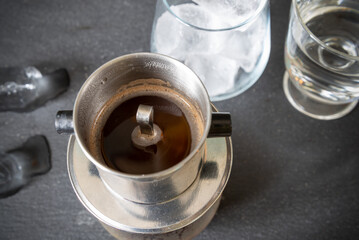A traditional Vietnamese way of brewing coffee using a special filter - phin. Coffee with condensed milk and ice. Top view.