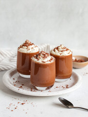 Healthy vegan chocolate mousse with vegan cream topping in glasses on white background. Homemade Chocolate mousse from aquafaba. 