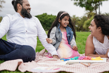 Happy indian parents having fun with little daughter at city park - Family love concept