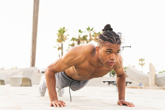 Black man doing push ups on street