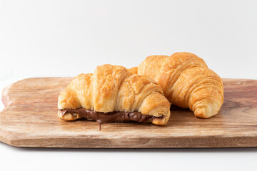 Traditional croissant stuffed with hazelnut on cutting board.
