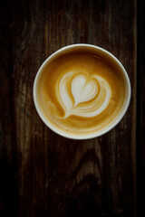 A cup of cappuccino with a heart latte art. Vintage wooden background, top view.