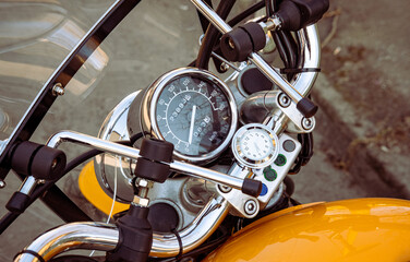 Fototapeta premium Motorcycle speedometer and dashboard with wind glass. Shiny, custom, stylish, yellow motorbike panel fragment close up. Retro design transportation. Freedom, speed and vehicle repair workshop concept