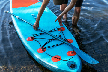 Man faceless with stand up paddleboard blue SUP on the water lake with paddle male legs active...