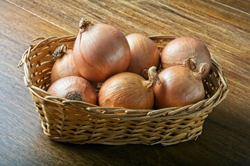 Wicker basket filled with onions on a dark wooden table