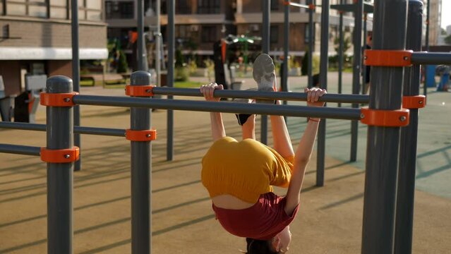 Girl somersaults on the bar slow motion outdoors