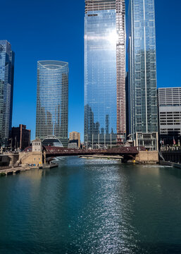 Chicago River sparkles with morning sunlight which is also reflecting off of building under construction at Wolf Point